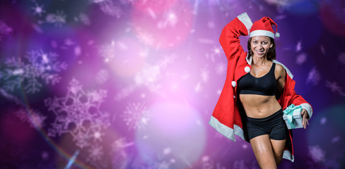 Portrait of happy athlete with hand behind head holding Christmas gift against purple snow flake pattern design