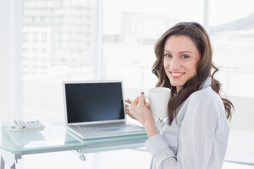 Fototapeta na wymiar Businesswoman with coffee cup in front of laptop in office