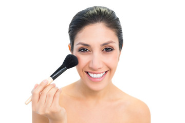 Brunette using a powder brush and smiling