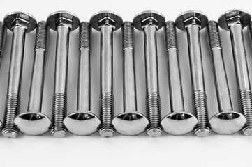 Long metal bolts for fastening parts, laid in one transverse row on a white background.