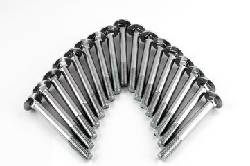 Metal bolts for fastening parts, stacked next to each other in the form of an arc on a white background.