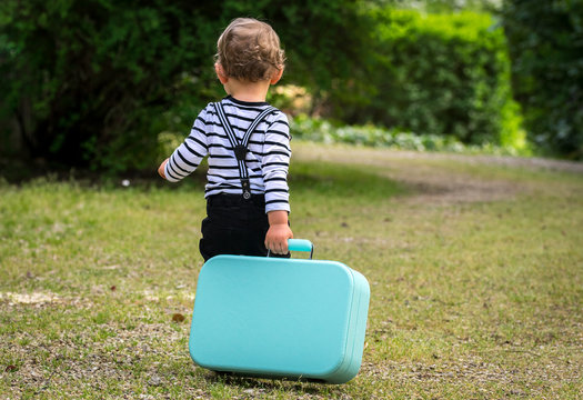 un petit gar&ccedil;on part en tra&icirc;nant une valise derri&egrave;re lui