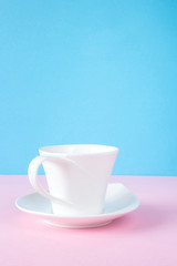 White ceramic cup on a pinkish blue background in minimalism style