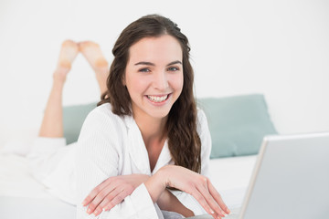 Relaxed smiling casual brunette with laptop in bed