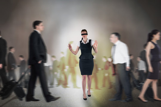 Composite image of redhead businesswoman in a blindfold walking through crowd