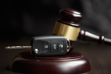 Close-up Of Gavel And Car Key On Sounding Block Against Grey Background