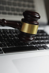 Law legal concept photo of gavel on computer with legal books in background.