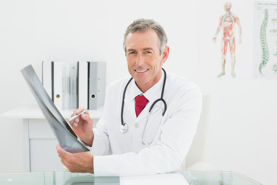 Smiling doctor with xray picture of lungs in office