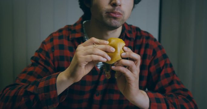 Young man eating hamburger in slow motion