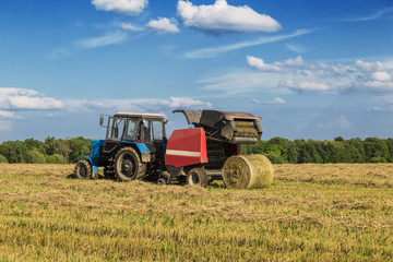 Obraz premium Straw harvesting with the help of a rotary roll forming machine in the unit with a tractor