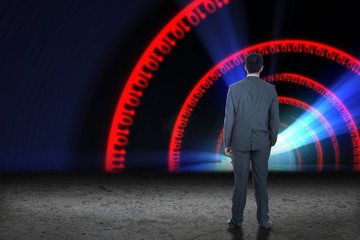 Businessman standing against binary code tunnel in red