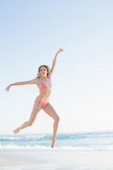 Fototapeta na wymiar Beautiful blonde woman jumping on the beach