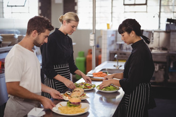 Young wait staff with fresh food in plates on kitchen counter