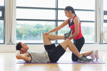 Fototapeta na wymiar Female trainer assisting man with his exercises in gym