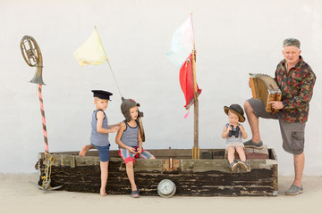 Three сute boys with father on pirate ship as sailors on summer evening. Children have fun outdoors. Happy kids on holiday in village. Home show with vintage boat and a white chicken. Adventures going