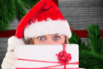 Festive blonde holding a gift against festive bow over wood