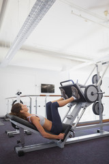 Fototapeta na wymiar Fit woman using weights machine for legs