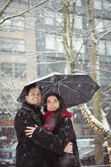 Couple embracing in street during snowfall