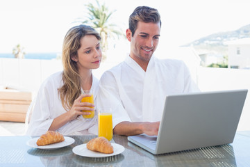 Fototapeta na wymiar Couple using laptop on breakfast table