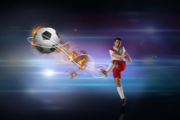 Fototapeta na wymiar Football player in white kicking against black background with spark