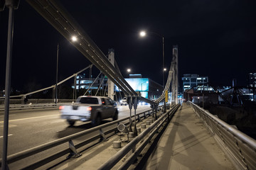 Fototapeta na wymiar Modern steel bridge with traffic driving into the city center at night