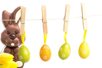 hanging easter eggs against yellow tulips with cute chocolate bunny