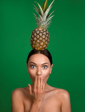 Portrait of bare girl with dazed face holding pine on head and covering mouth with hand. Isolated on background