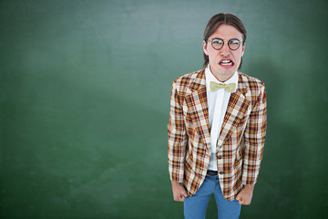Furious geeky hipster looking at camera against green chalkboard