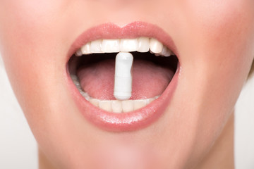 Naklejka premium Film tablet between the teeth of a woman