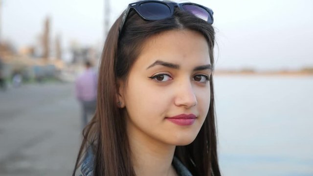 Portrait of a lovely young woman standing on the Dnipro embankment. She smiles with sparkles in her beautiful eyes in spring in slo-mo.