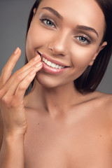 Close up of happy female face with nude decollete touching her soft lips