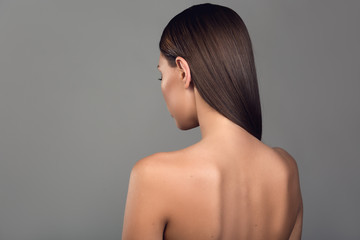 Back of naked woman showing groomed skin. Isolated on background