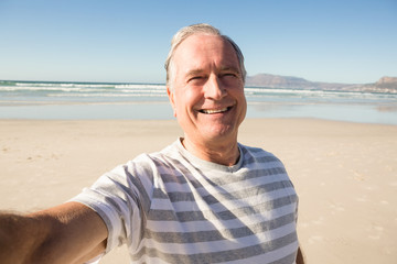 Portrait of happy senior man standing at beach
