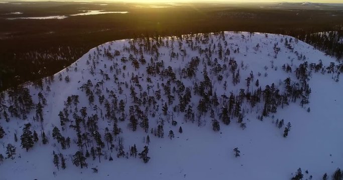 Aerial view around a fjeld fell mountain, in endless arctic tundra wilderness, on a sunny winter morning dusk, in luosto, Pyha-luosto national park, Pelkosenniemi, Lapponia, Finland