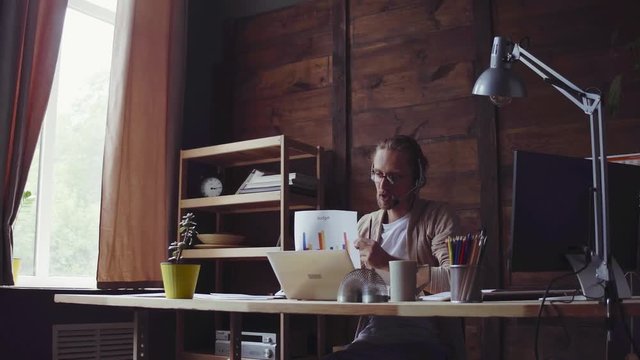 Young freelancer working in flat office. Sitting at desk and looking through papers. Freelance business concept.