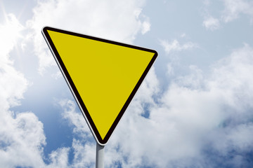 Hazard triangle against bright blue sky with clouds