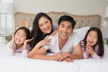 Cheerful family of four lying in bed