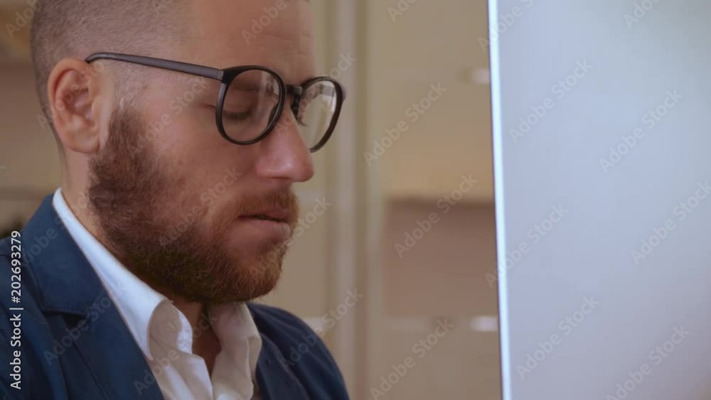 Poster portrait successful bearded man sitting at the working place in front of display computer. handsome white collar manager at work