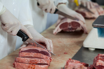 Butcher cutting meat at meat factory