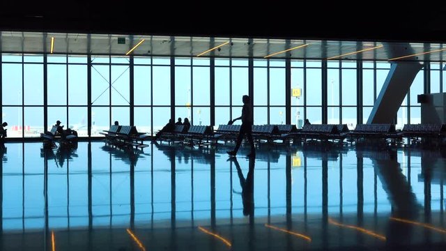Modern glass waiting room in airport with passenger`s silhouette 