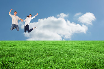 Couple jumping and holding hands against cloudy sky