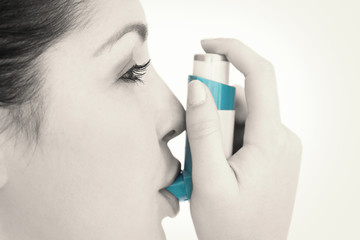 Woman with an asthma inhaler against white background
