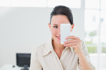 Businesswoman holding cellphone on eye