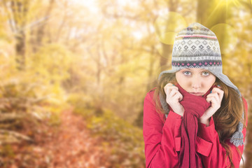 Cold redhead wearing coat and hat against tranquil autumn scene in forest