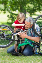 Happy father and his son fixing a bike 