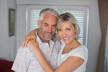 Smiling woman embracing mature man at home