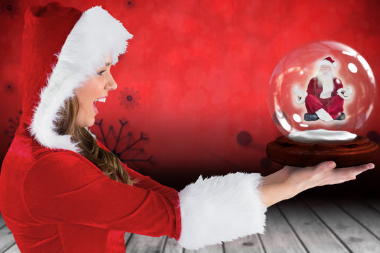 Composite image of sexy santa girl holding snow globe against snowflake wallpaper over floor boards