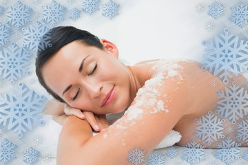 Obraz na płótnie Canvas Peaceful brunette lying with salt scrub on shoulders against snowflake frame