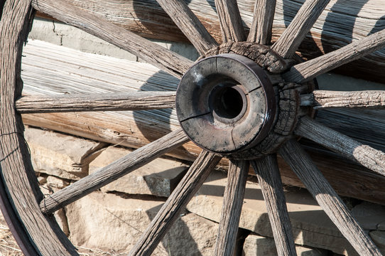 A weathered wagon wheel sits outside the livery stable at Old Trail Town