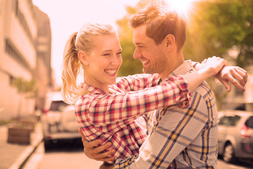 Obraz premium Couple in check shirts and denim hugging each other on a sunny day in the city
